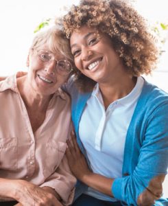 Smiling caregiver with arm around female client